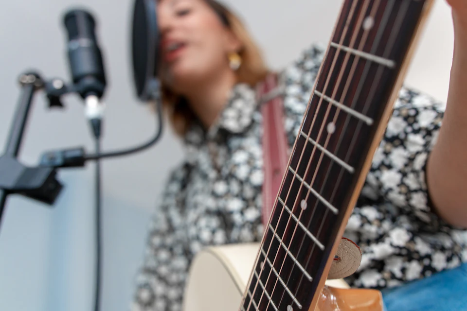 Cantante con guitarra acústica ante un micrófono de condensador