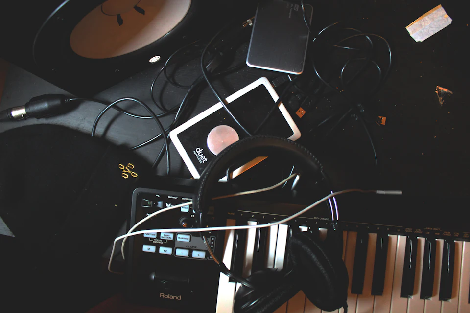 Auriculares, teclado MIDI y altavoz sobre una superficie negra